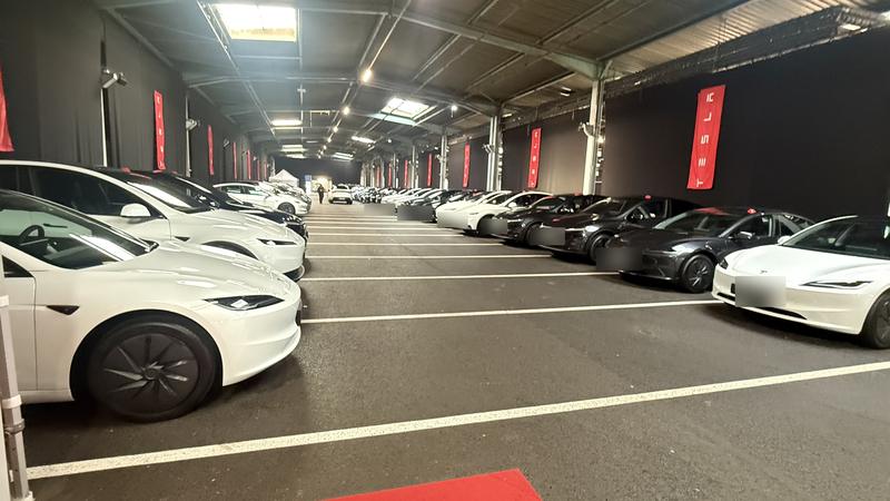 Tesla neuves blanches et noires alignées dans le hall de livraison